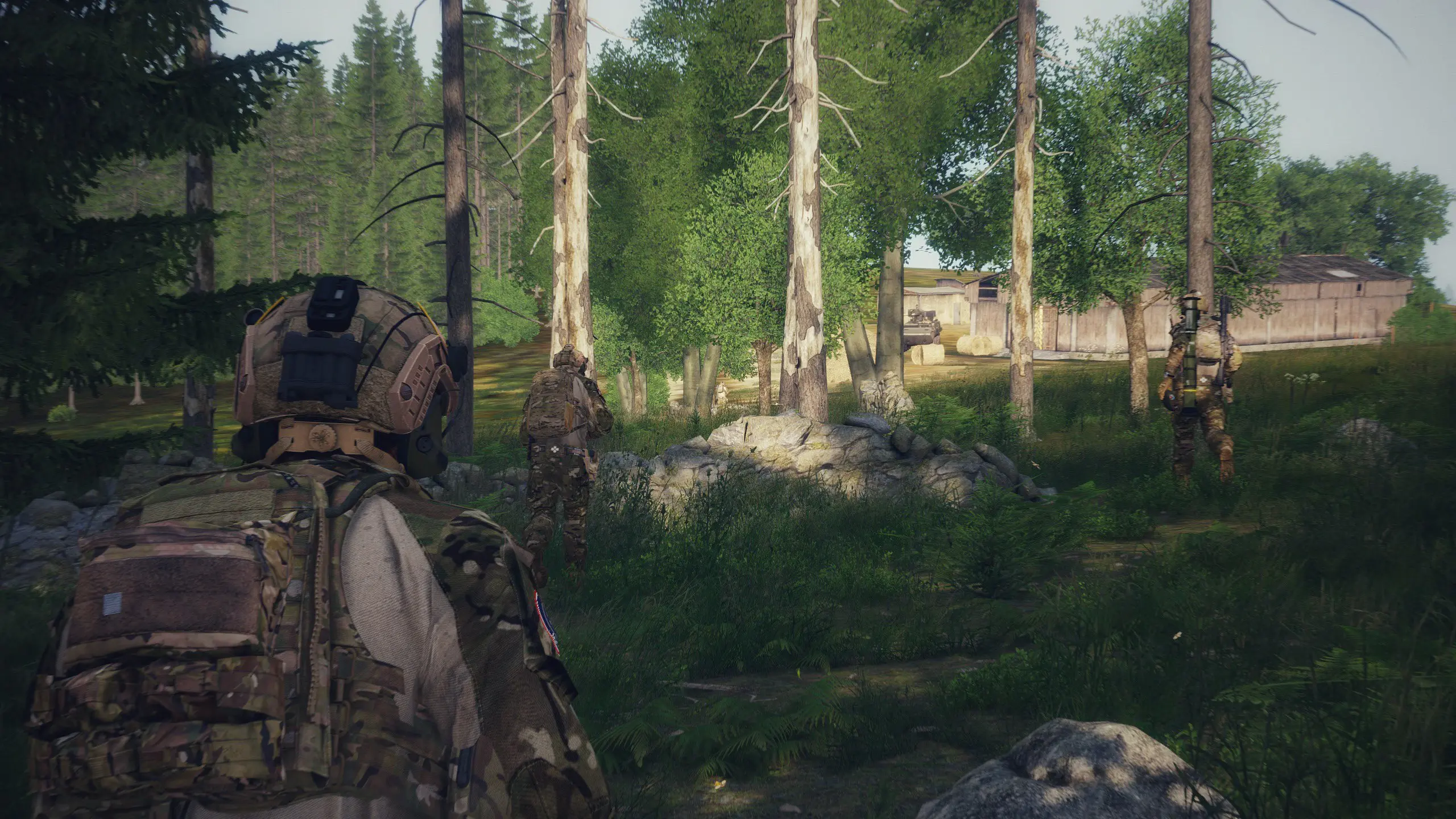 A photo of three people holding rifle walk towards a Pandur II APC in a compound next to a forest